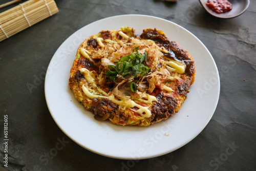 okonomiyaki, Traditional Japanese Pizza, Japanese hot plate pizza from Okonomiyaki. made of flour which is diluted with water or dashi, plus cabbage, chicken eggs, seafood and fried in a teppan