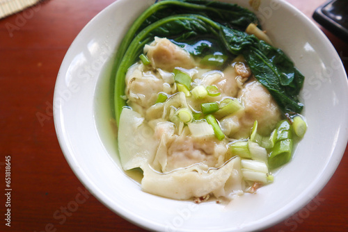 wonton soup. Bowl of wonton soup with chili oil. Shrimp or meat dumpling soup with mustard , green onions,