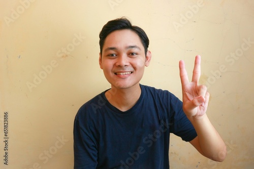 Excited Asian man wearing navy blue shirt with various expressions, on isolated yellow background