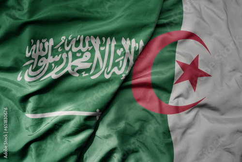big waving realistic national colorful flag of saudi arabia and national flag of algeria .