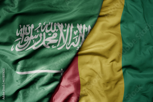 big waving realistic national colorful flag of saudi arabia and national flag of guinea .