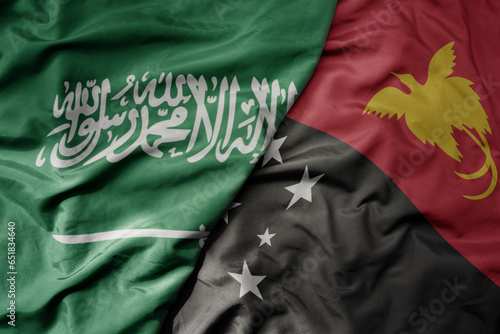 big waving realistic national colorful flag of saudi arabia and national flag of Papua New Guinea .