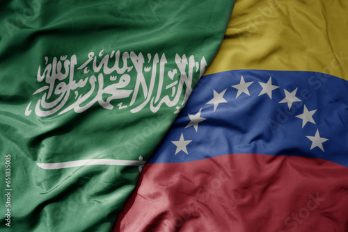 big waving realistic national colorful flag of saudi arabia and national flag of venezuela .
