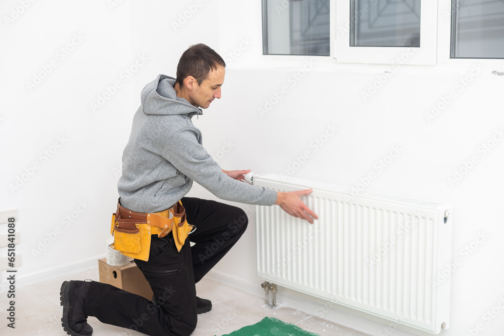 Man is repairing radiator battery in the room. Maintenance repair works renovation in the flat. Heating restoration