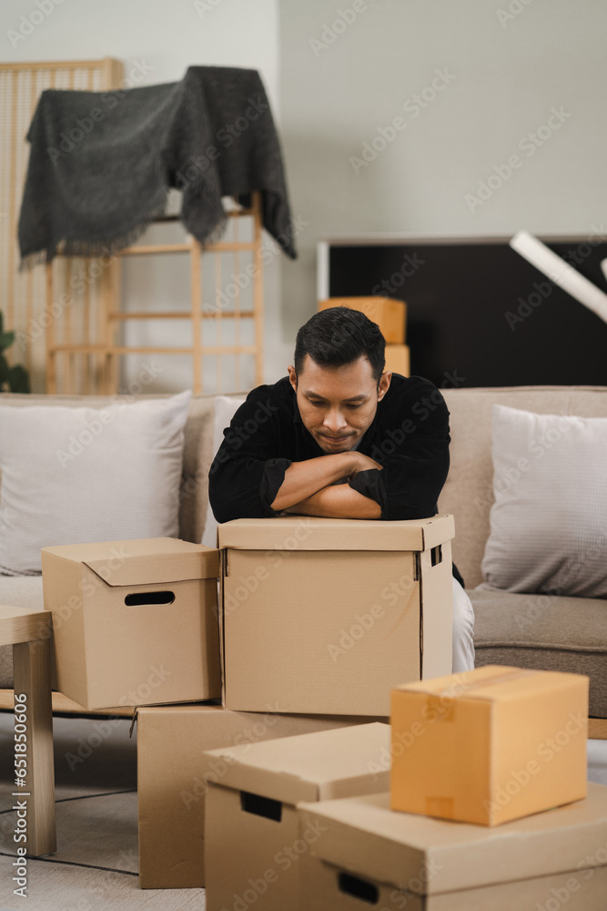 Φωτογραφία Exhausted Male sit rest on sofa in living room near heap of cardboard boxes feel unmotivated to unpack their belongings
