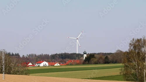 renewable energy, bavarian landscape with church in the centre, a wind mill in the background and hot flickering summer air
