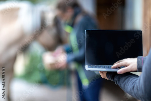 Bilde på lerret Horse owner as digital online clients: A laptop in front of blurred horse and ow