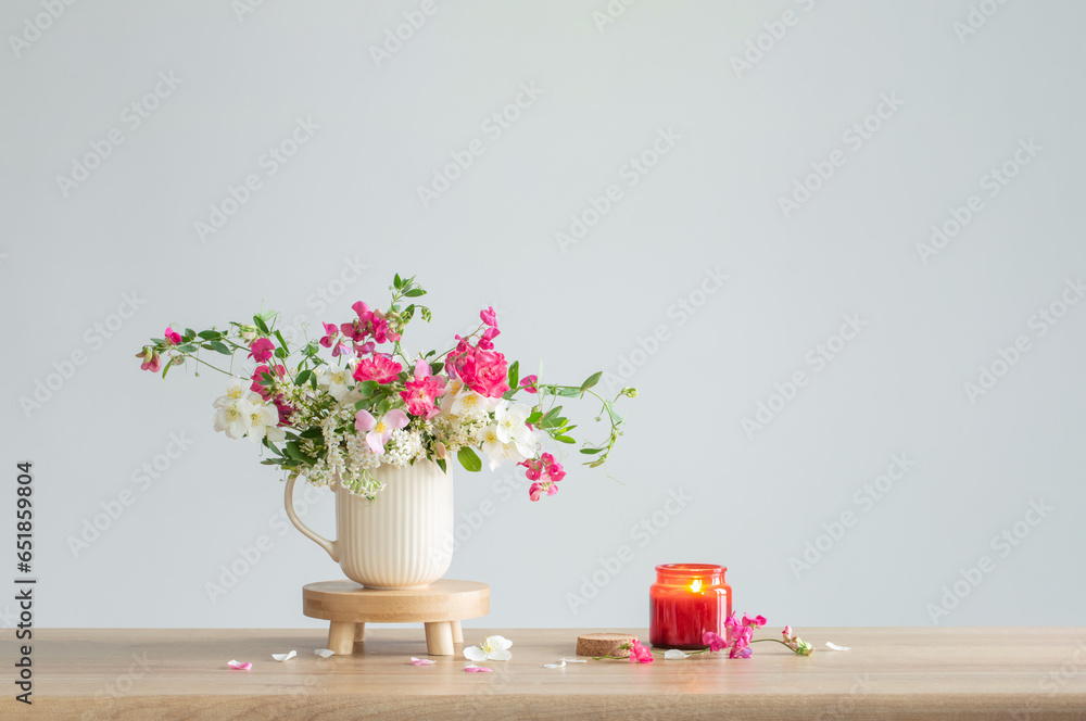 summer flowers and burning candles   on light  background