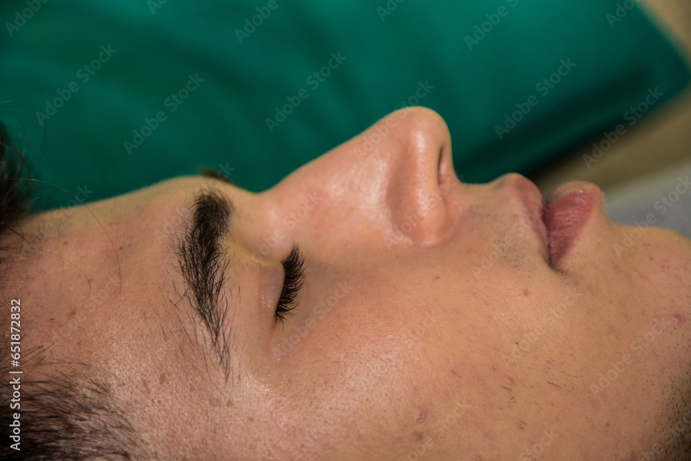 Naklejka premium A close up of a handsome young man laying down with his eyes closed