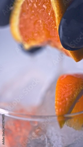 氷の入ったグラスにオレンジを絞る