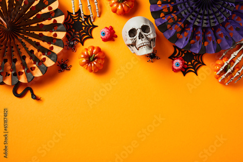 Happy Halloween composition. Flat lay Halloween decorations, pumpkins, paper fans, skeleton hands, spiders, bloody eyes on orange background