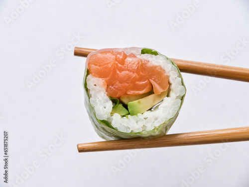 Tasty sushi roll with wooden chopsticks on white background