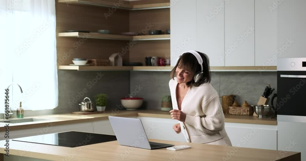 A spirited Caucasian woman, donning headphones, dances with joy in her kitchen. Her lively moves and upbeat rhythm infuse the kitchen with positive energy, creating a lively and vibrant atmosphere. A spirited Caucasian woman, donning headphones, dances with joy in her kitchen. Her lively moves and upbeat rhythm infuse the kitchen with positive energy, creating a lively and vibrant atmosphere.