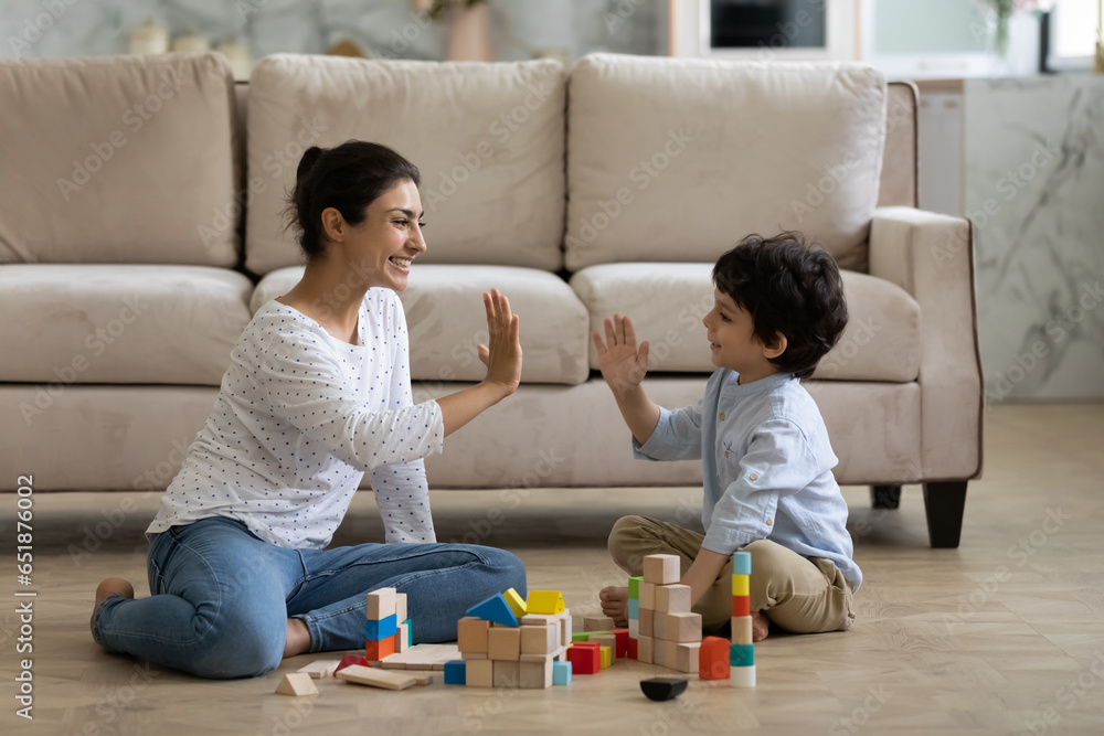 © fizkes - Happy Indian mother and 5s son giving high five, sitting on warm floor at home, smiling young mom with boy child having fun, playing with colorful wooden construction toys, spending leisure time © fizkes - Happy Indian mother and 5s son giving high five, sitting on warm floor at home, smiling young mom with boy child having fun, playing with colorful wooden construction toys, spending leisure time