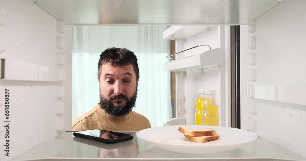 A bewildered Caucasian man, perhaps after a lively party, opens the fridge and is astonished to find his phone inside. His facial expression reflects the unexpected discovery. A bewildered Caucasian man, perhaps after a lively party, opens the fridge and is astonished to find his phone inside. His facial expression reflects the unexpected discovery.