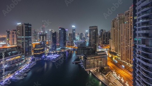 Aerial view to Dubai marina skyscrapers around canal with floating boats all night