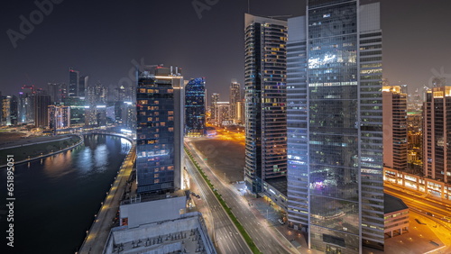 Panorama showing cityscape of skyscrapers in Dubai Business Bay with water canal aerial night
