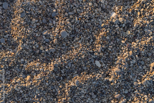 Smooth round pebbles on a Mediterranean beach with sunset light