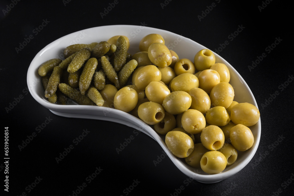 kidneyshaped tray with pickles and olives, placed on a black