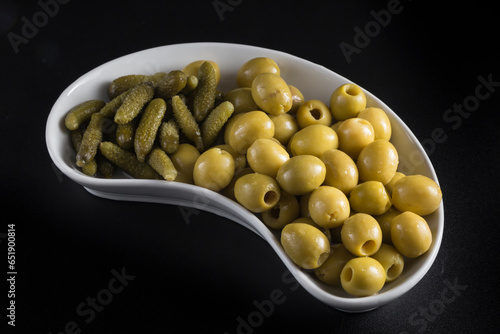 kidney-shaped tray with pickles and olives, placed on a black background