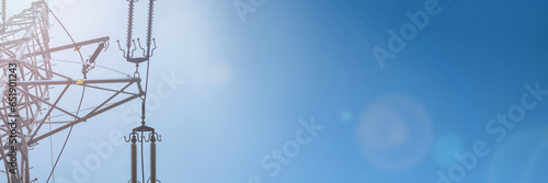 Against the background of the sky, a delicate lens flare and a high voltage overhead line pole. © fotodrobik