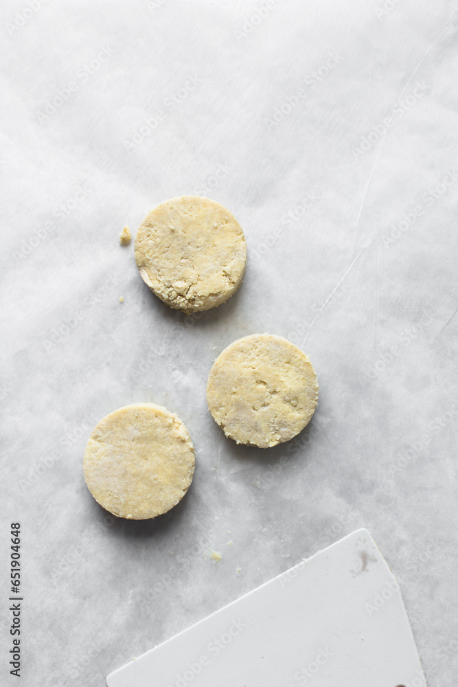 Raw scones on a parchment lined baking sheet, yogurt scones about to be baked, Unbaked buttermilk scones, process of making scones Raw scones on a parchment lined baking sheet, yogurt scones about to be baked, Unbaked buttermilk scones, process of making scones