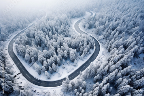 Aerial curved road in the winter season with snow covering on surrounded trees on the mountains.