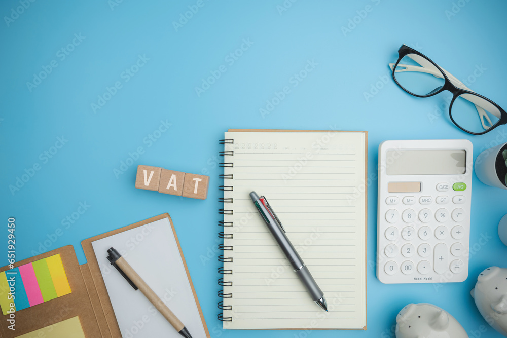 Top view VAT on wood cubes blocks on a blue background with copy space calculate annual taxes concept. Accounting, Vat, income tax. Calculation of taxes annual years. Top view VAT on wood cubes blocks on a blue background with copy space calculate annual taxes concept. Accounting, Vat, income tax. Calculation of taxes annual years.