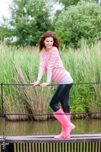 woman wearing rubber boots with umbrella in spring nature