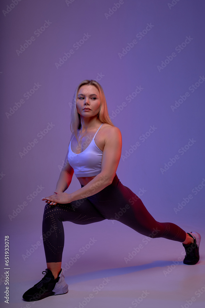 skilled sportswoman doing lunges exercises for leg muscle. Active girl doing front forward one leg step lunge exercise for butt, isolated on purple background. full length shot