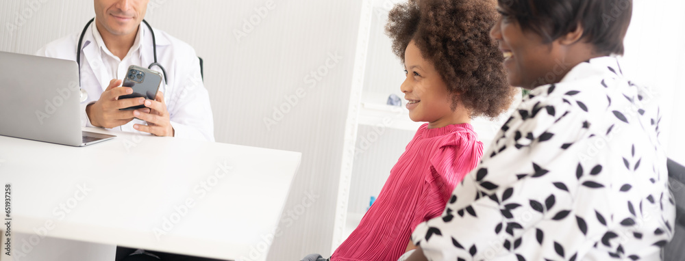 Fototapeta premium Hispanic physician meeting and diagnosis mixed-race afro children with her African American mother at a hospital. The doctor using stethoscope and do the medical exam on the laptop and mobile phone.