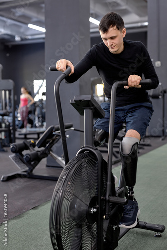 slim fit guy using stationary bike at sport center, full length shot © alfa27