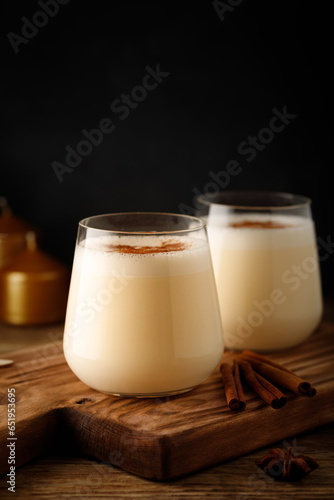 Festive eggnog cocktail in a glass on a black background