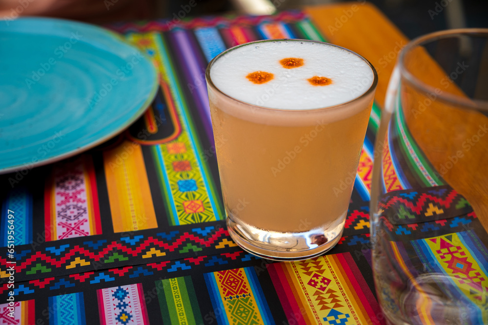 Pisco Sour cocktail in glass on placemat with traditional pattern