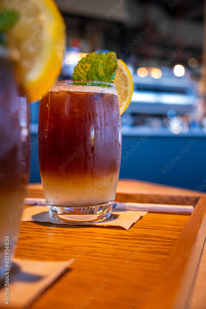 Cold layered coffee drink with lemon slice and mint leaf