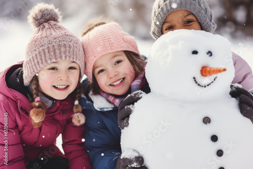 Group of diverse happy multi-ethnic children making snowman and having fun outdoors in snow, winter time