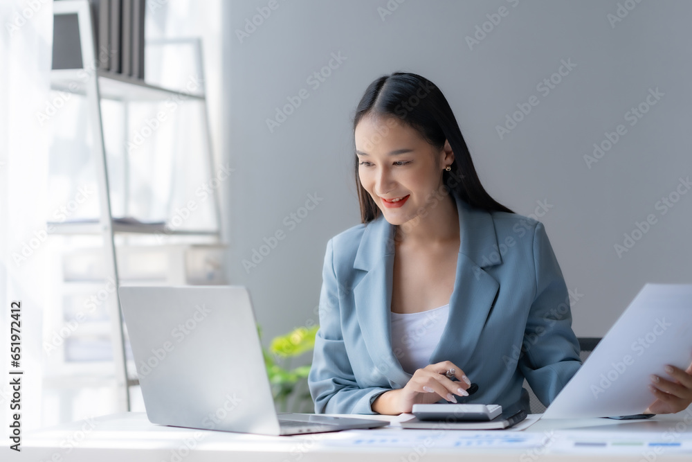 Cute, charming Young Asian businesswoman working with document and laptop in the office. Cute, charming Young Asian businesswoman working with document and laptop in the office.