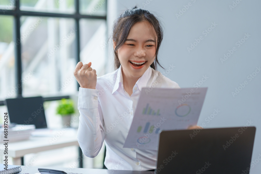 Happy asian businesswoman raising hands with victory smiling happily with laptop computer. The concept of success at work.