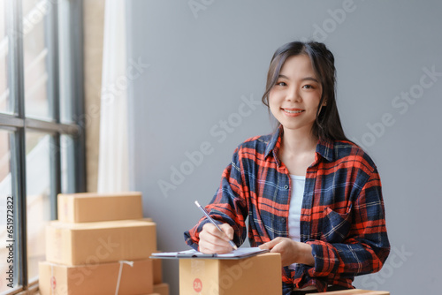 E-commerce Entrepreneurship. Asian Female Online Seller Packing Orders for Internet Sales. Efficient Online Sales. Asian Female owner Packaging Products for Delivery.