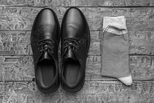 Black and white image of men's shoes and socks on a wooden background. The concept of men's shoes.