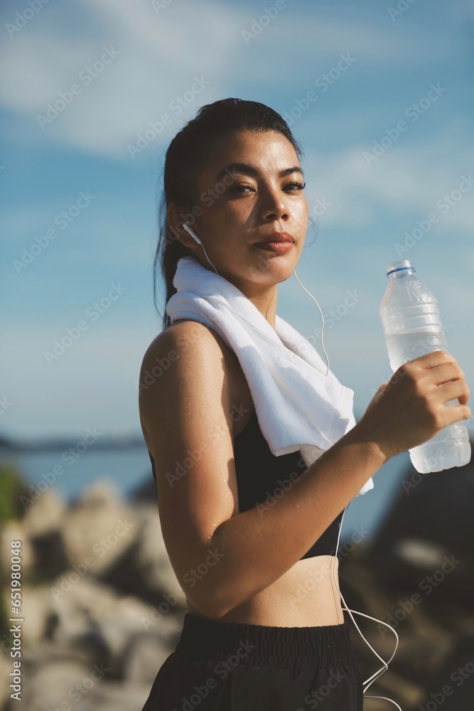 Beautiful woman drinking water after workout on the beach. Beautiful woman drinking water after workout on the beach.