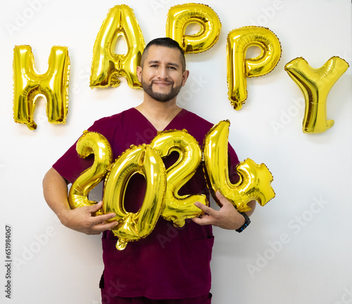 Young health worker of Latin appearance with a white background, holding numbers made with balloons alluding to the new year. photo