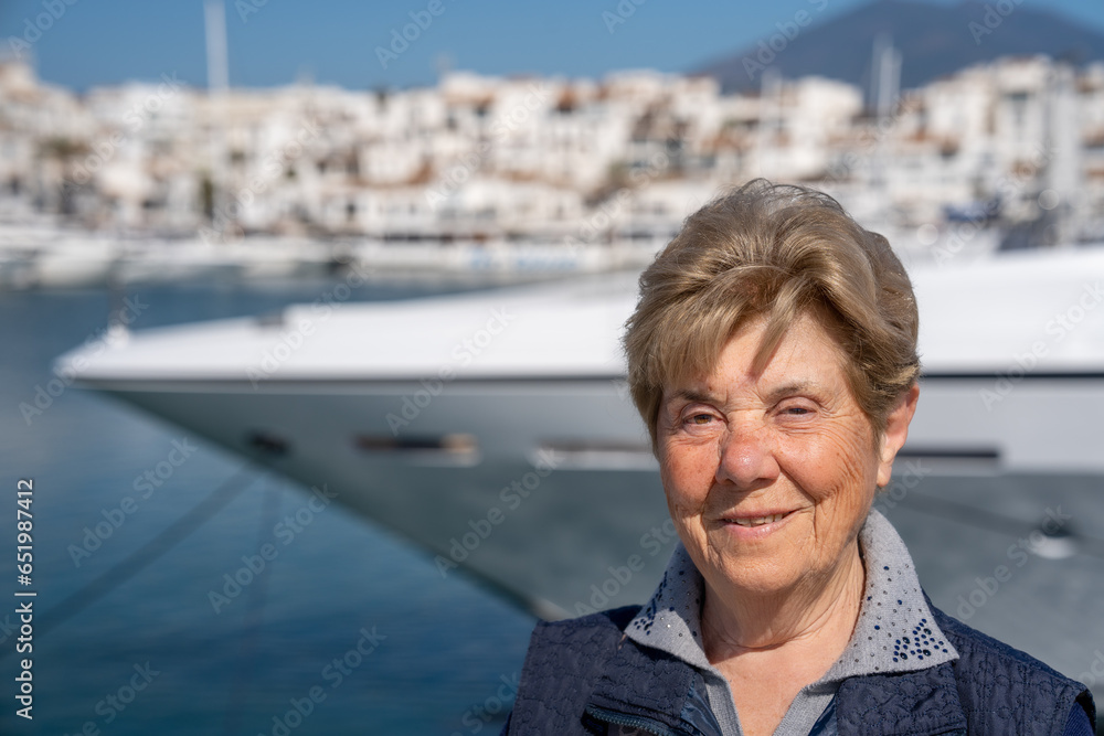 Fototapeta premium An elderly retired woman on holiday, a city port in the background