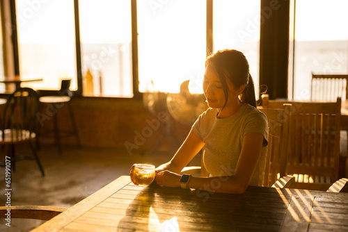 Woman in coffee shop under sunset sunlight flare photo