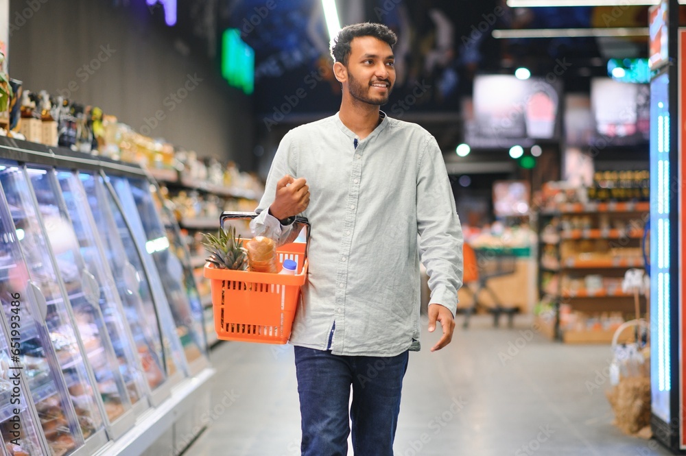 Portrait of happy handsome young Indian at grocery shop or supermarket.