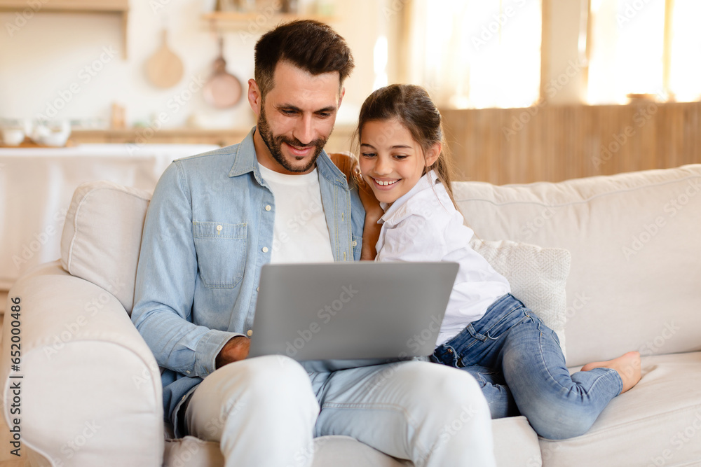 Cheerful daddy and daughter having fun with laptop at home Cheerful daddy and daughter having fun with laptop at home