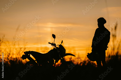 silhouette of a motorcycle and a motorcyclist at sunset in a field, enduro off-road motorcycle