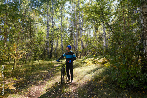 mountain bike.A man in a protective helmet walks with a bicycle through the forest in autumn.Active lifestyle
