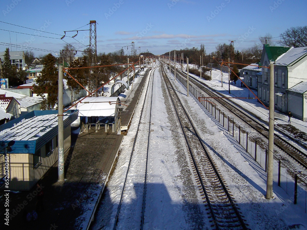 Fototapeta premium A small railway station with railway tracks in perspective in the city