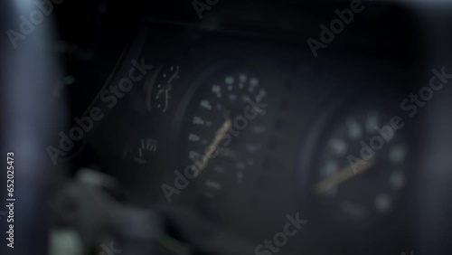 Close view of the dashboard and speedometer of an abandoned and dilapidated 1970s rally car resting in a scrap yard. The car has spider webs and dust on all surfaces.  photo